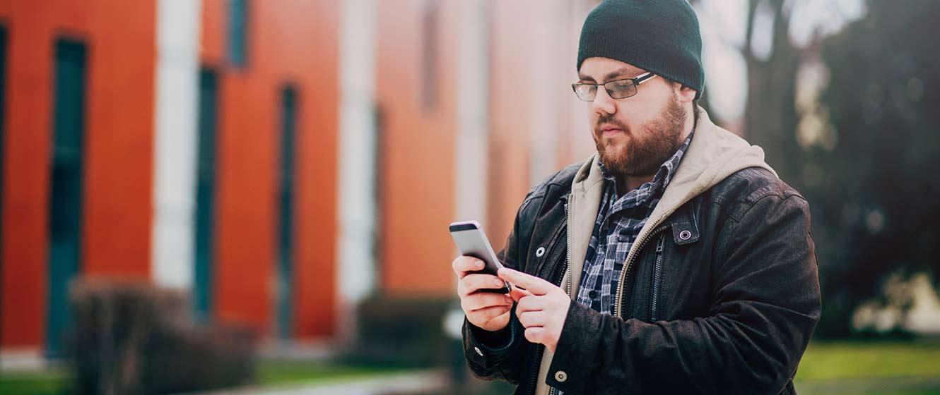 Image of a man using his smart phone, walking outdoors