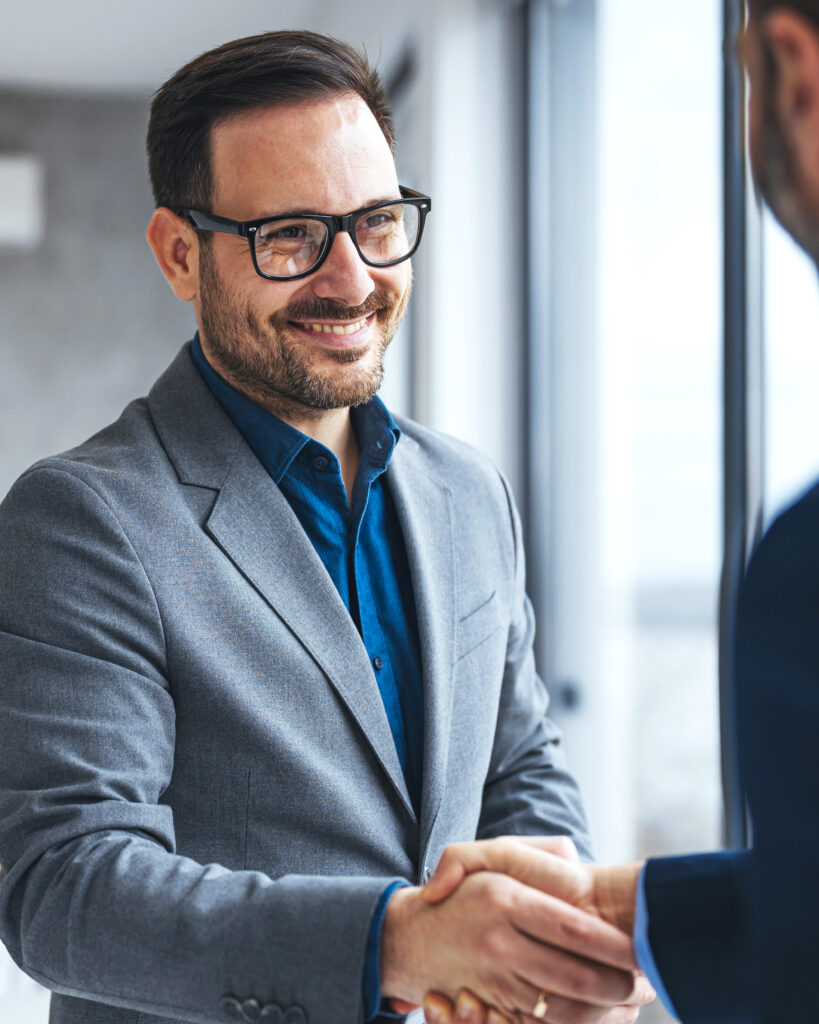 Smiling professional man shaking hands with someone in an office